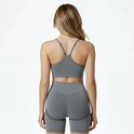 Achterkant van een model met blonde haren, draagt een grijze sport BH en een grijze short.