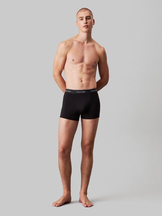 Man met een zwarte Calvin Klein boxer, met logo op de tailleband.