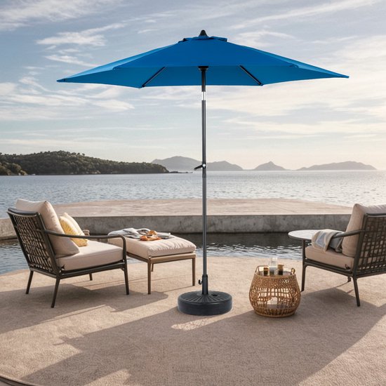 Blauwe parasol op een terras aan het water, met twee stoelen en bijzettafel.