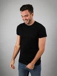 Een lachende man met een zwart Suitable T-shirt en blauwe jeans.