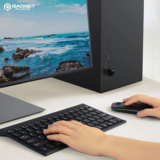 Zwarte Gadgetplace USB Bluetooth adapter aangesloten op een computerkast, met toetsenbord en muis in gebruik.