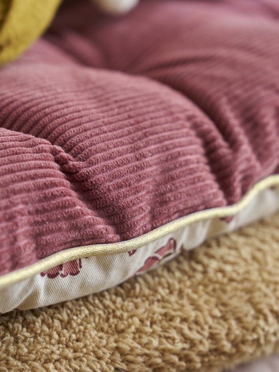 Detail van een lichtroze corduroy vloermatras met een goudkleurige bies en bloemenprint.
