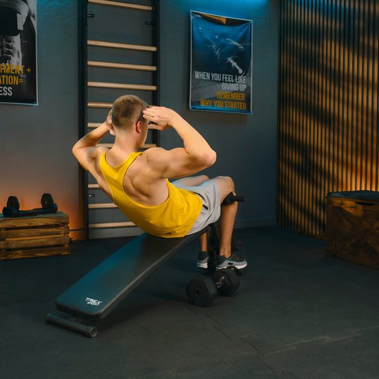 Man in geel sport-top doet buikspieroefening op de schuine trainingsbank.