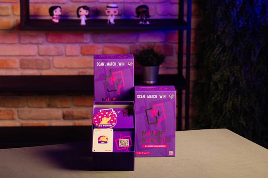 Twee paarse dozen van "Music Match" naast een open displaydoos met kaarten en een "DJ TOKEn" kaart.