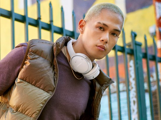 Man met blonde coupe draagt een witte Bose koptelefoon.