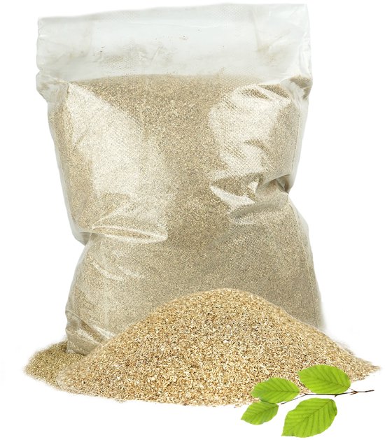 Un sac transparent de sciure de fumage brun clair, posé sur un tas du même matériau avec trois feuilles vertes sur le côté.