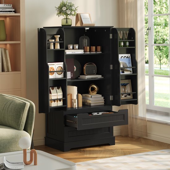 Zwarte opbergkast in een woonkamer, met geopende deuren en een lade vol spullen, naast een raam.