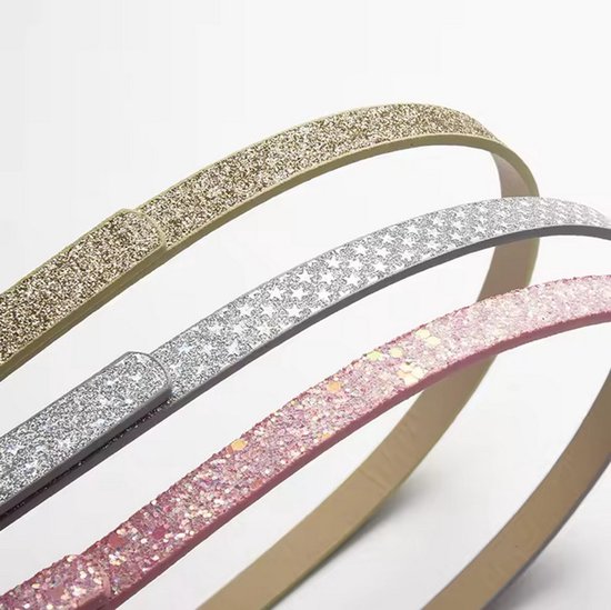 Close-up van drie smalle glitter riemen in roze, zilver en goudkleurig.