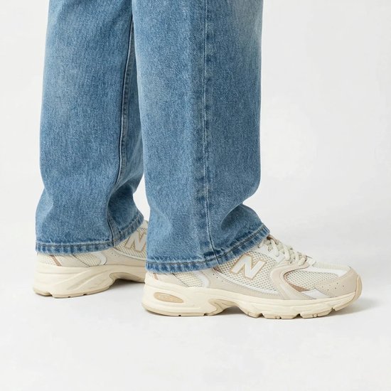 New Balance 530 sneakers in beige met lichtblauwe jeans.