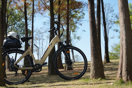 Lichtbruine elektrische fiets met zwarte details en bagagedrager, staand tussen bomen.