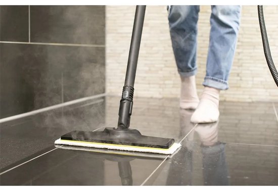 Gros plan du nettoyeur vapeur nettoyant un sol carrelé gris foncé.