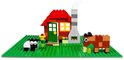 LEGO boerderij met rode huis, schoorsteen, schaap en bruine koe op groene bouwplaat.