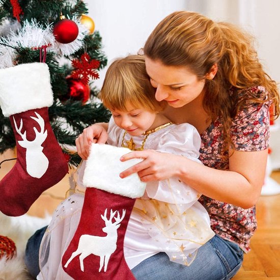 Mère et enfant décorent une chaussette de Noël avec un bord blanc et une application de cerf blanc.