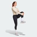 Vrouw in een beige longsleeve shirt en zwarte legging met driestrepen op de enkel.