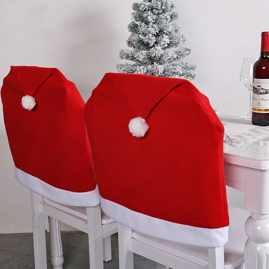 Twee rode stoelhoezen in de vorm van een kerstmuts met witte rand en pompon op witte stoelen.