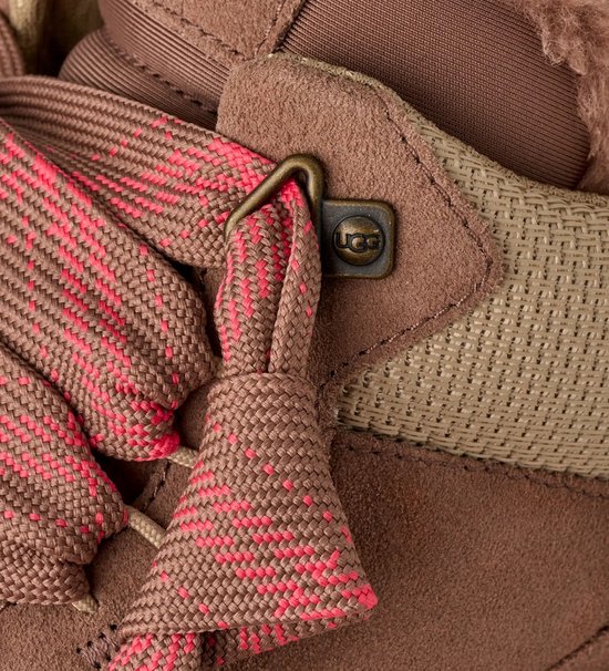 Detail van bruine UGG sneaker met roze veters en UGG logo veteroog.