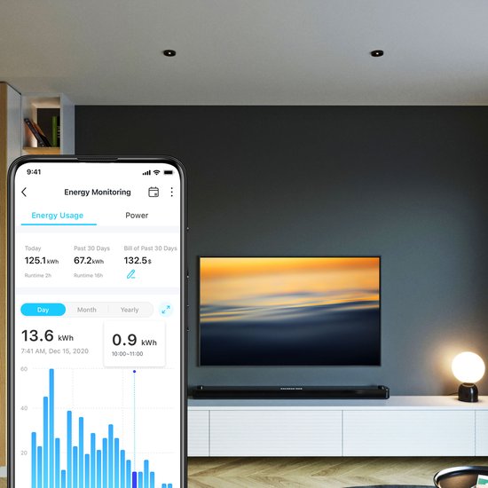 Een smartphone toont de energiebewakingsgrafiek van een Tapo slimme stekker, met een tv op de achtergrond.