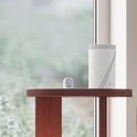 Witte Deco BE65 router met grijze lijnen, naast een kleine digitale thermometer op een houten tafel.
