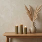 Drie taupe ribbelkaarsen op een houten tafel met een vaas met pampasgras.