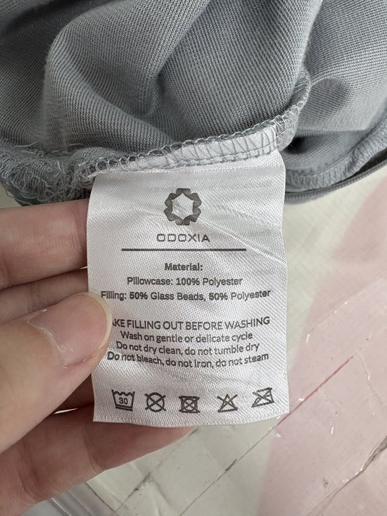 Kleine productielabel met wasinstructies voor het grijze Odoxia verzwaringskussen.