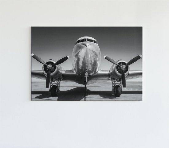 Une photo noir et blanc d'un avion vintage, vue de face sur une piste d'atterrissage.