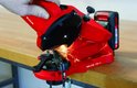 Rode Einhell kettingzaagslijper met vonken tijdens gebruik, vastgehouden door een hand.