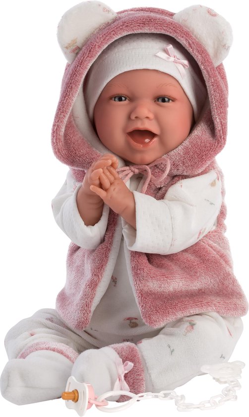 Lachende babypop Mimi met berenmuts en vestje, witte onesie met bloemetjes en speen.