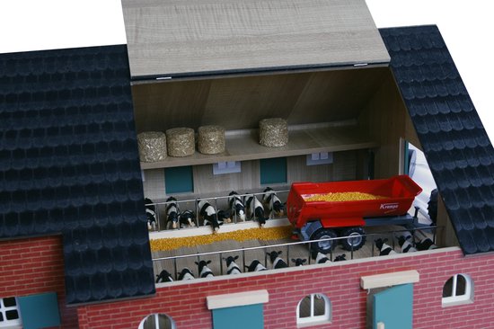 Speelgoedboerderij met in de stal zwart-wit koeien, een rode aanhanger met mais en een groene tractor.