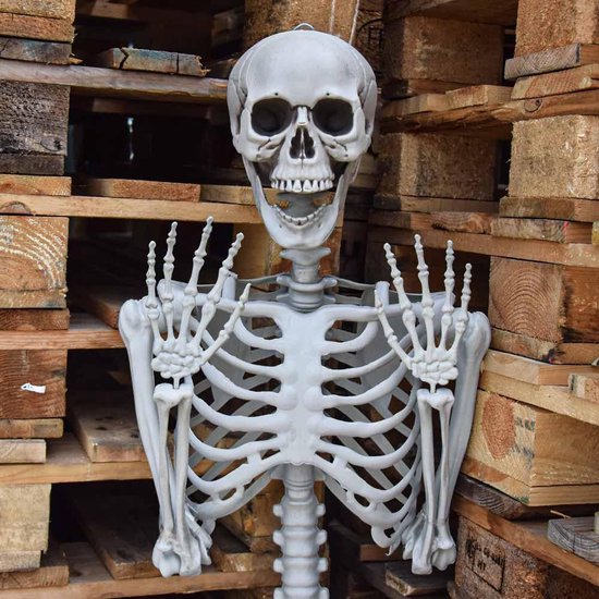 Een levensgroot skelet staat voor een stapel houten pallets.