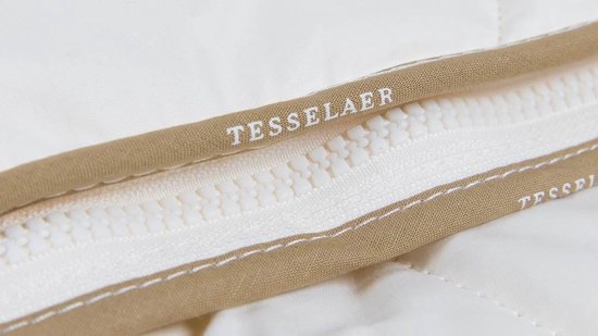 Detailopname van een witte rits met de tekst TESSELAER erop, omzoomd door beige randen.