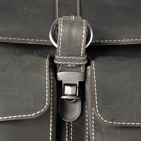 Détail de la fermeture à boucle d'un sac messager en cuir noir avec surpiqûres blanches.
