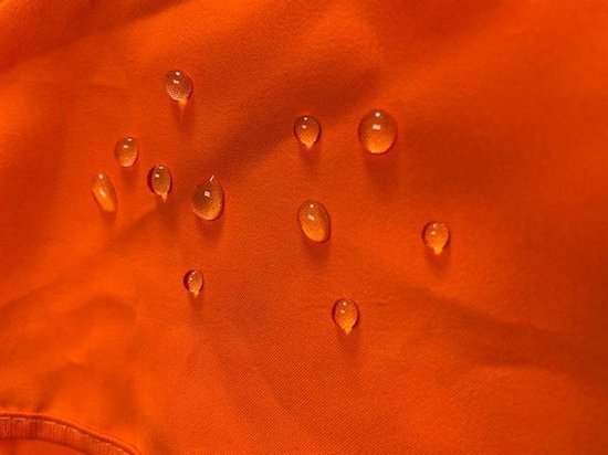 Waterdruppels op feloranje textiel.