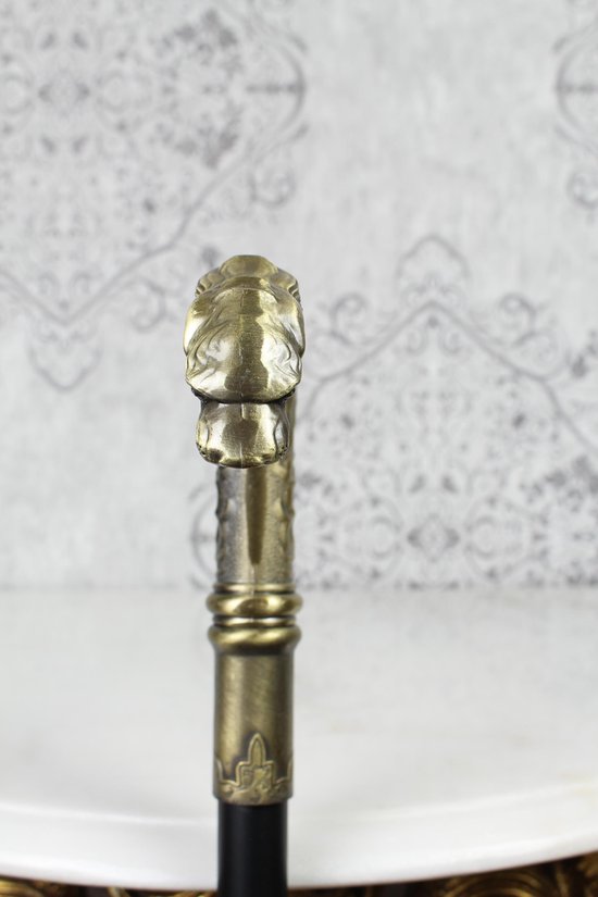 Gouden detail op het handvat van een wandelstok, met patronen en een eindkap.