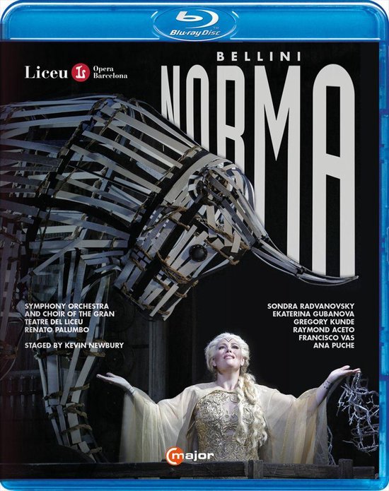 Bellini Norma opera Blu-ray hoes. Een vrouw in een gouden jurk staat op een podium voor een grote metalen olifantstructuur. Titel 'Norma' is groot weergegeven.