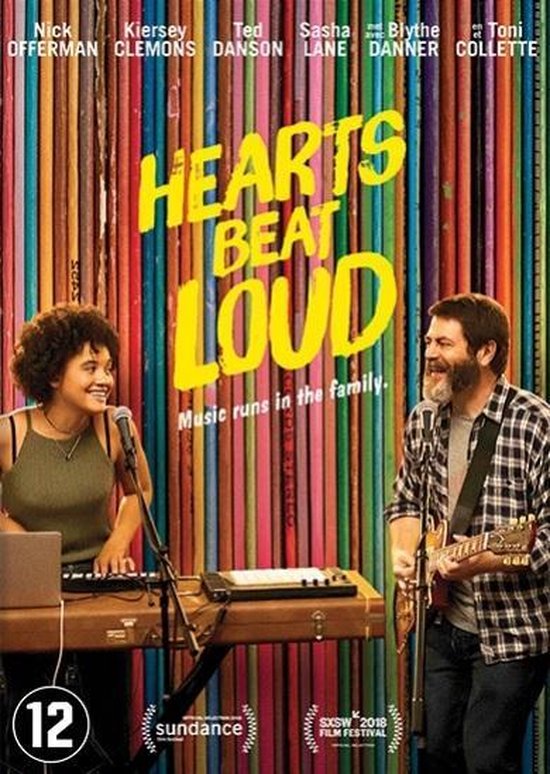 Filmposter met de titel 'Hearts Beat Loud'. Twee personen, een vrouw met een toetsenbord en een man met een gitaar, staan voor een muur van gekleurde boeken.