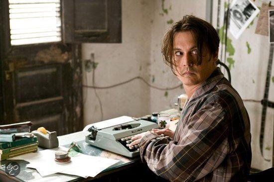 Johnny Depp met bruin en geel geruite pyjama, typend op een oude typemachine.