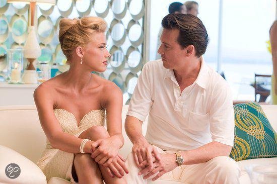 Scarlett Johansson en Johnny Depp zitten op een bank en kijken elkaar aan. Zij draagt een beige jurk.