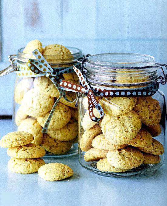 Twee glazen potten gevuld met lichte gele koekjes, versierd met linten.