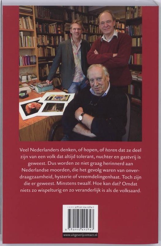 Drie mannen staan in een bibliotheek. Een man zit op de voorgrond.