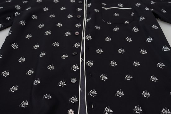 Donkere pyjama met witte bies en een all-over print van figuren.