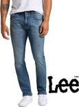 Man in een lichtblauwe jeans, staand met witte sneakers en het Lee-logo op de zijkant.