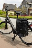 Zwarte Sparta e-bike met een zwarte zadeltas, geparkeerd in een buitenwijk.