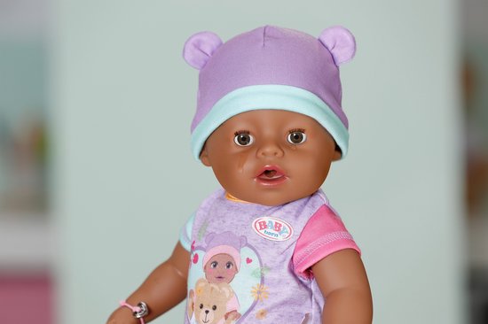 Close-up van BABY born Eva pop met paarse muts met oortjes en paarse bodysuit met berenprint. Baby heeft een speen in.