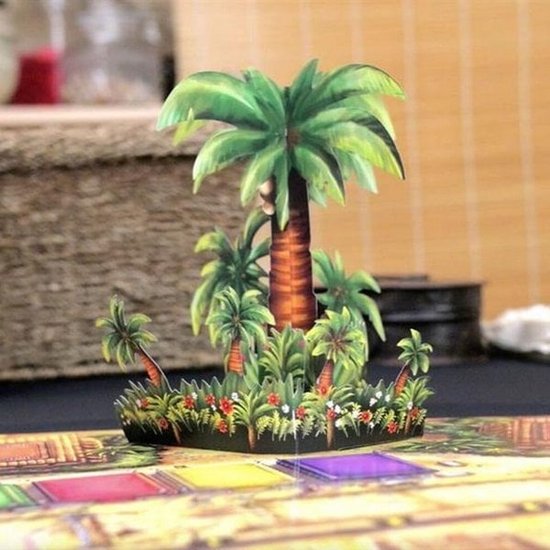Een kartonnen 3D-decorstuk met palmbomen en bloemen, passend op een bordspel.