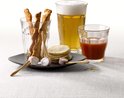 Verre de bière, verre de jus de tomate, verre avec des gressins, des tortillas et des rouleaux de viande.