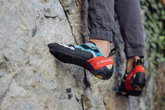 Klimschoenen in zwart, blauw en rood op een rotswand.