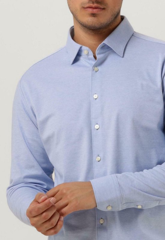 Homme portant une chemise Desoto bleu clair et lissant sa manche.