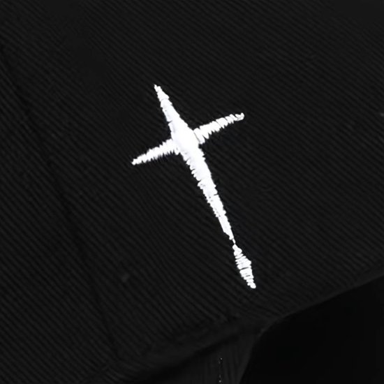 Detail van een witte kruisborduur op een zwarte baseballpet.