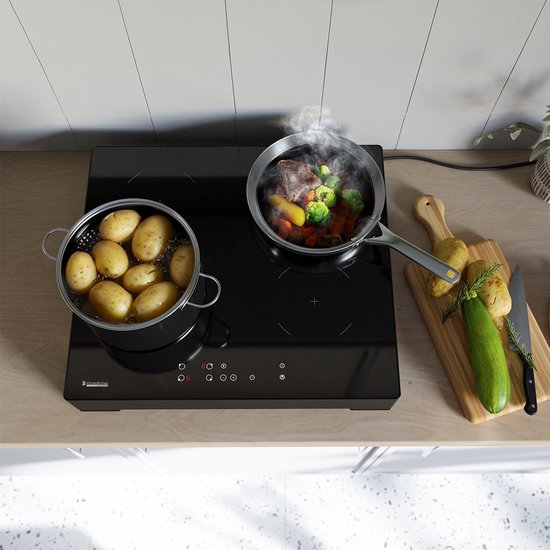 Plaque de cuisson à induction KitchenBrothers noire avec deux casseroles et des légumes sur une planche à découper.