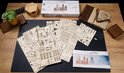 Een tafel met uitgepakte onderdelen van het Ugears Harry Potter™ Zweinstein modelbouw-pakket.